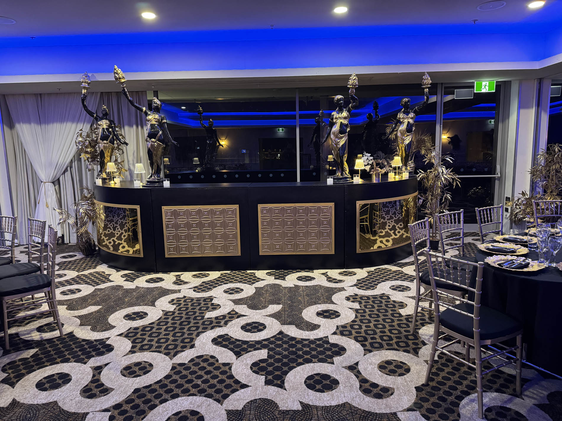 Martini glass centrepieces with feathers and pearls on black and gold table setting