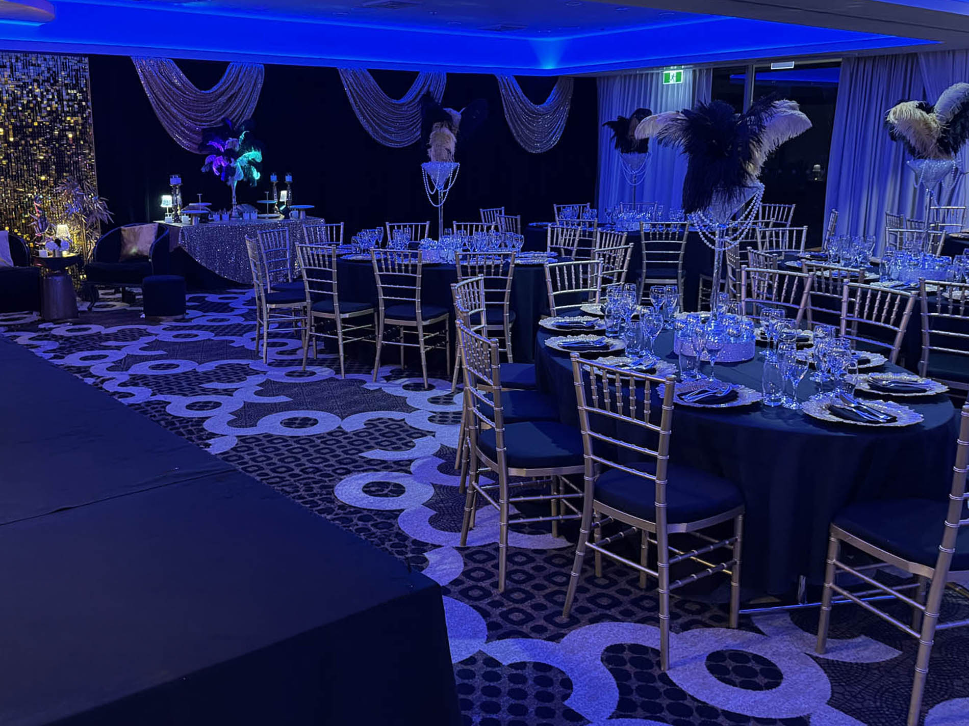 Gold-edged Great Gatsby cake display with feather arrangement and mirrored candle columns