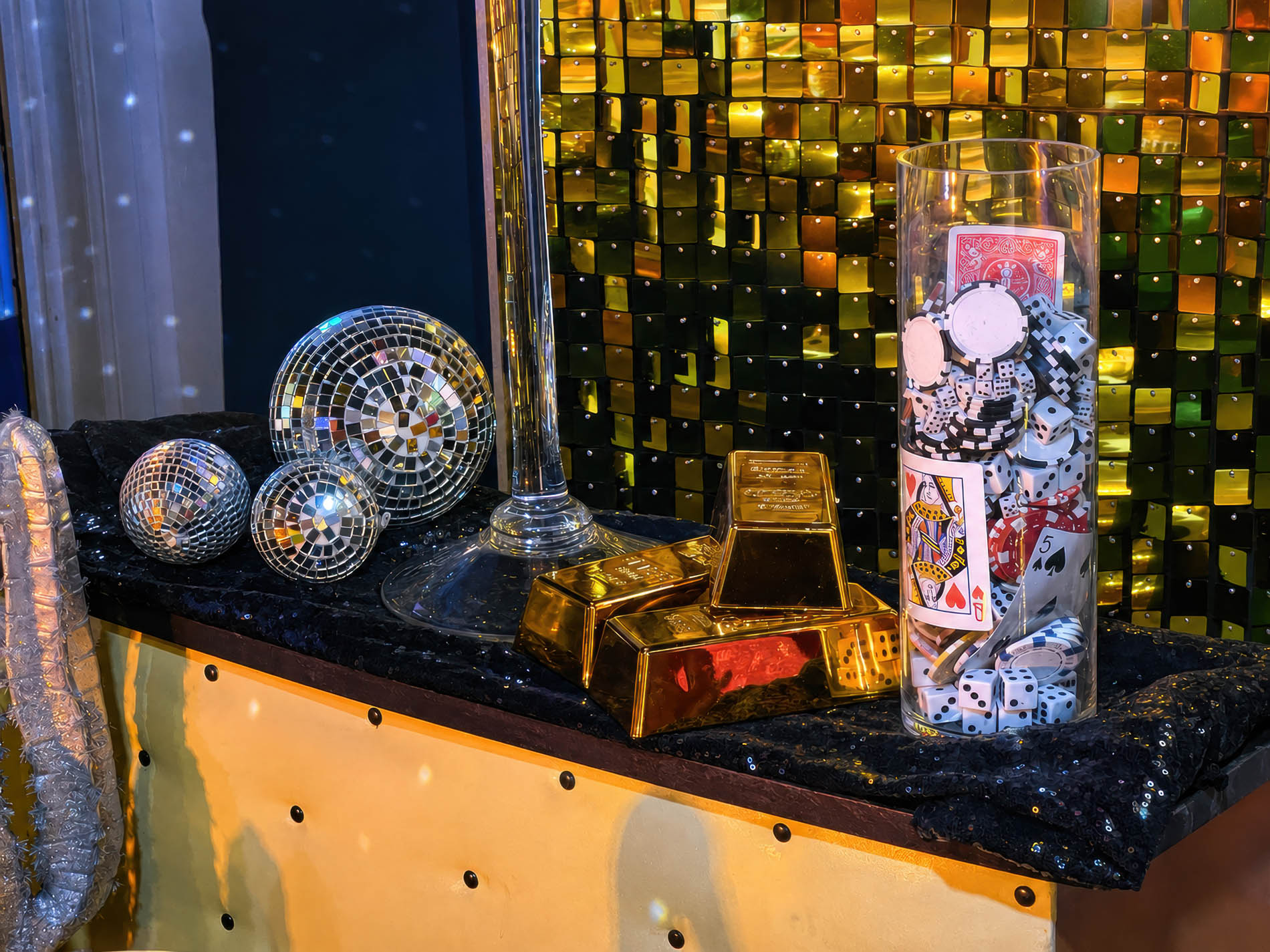 Gold nuggets, playing cards, dice, and disco balls styled against a gold sequin wall for the casino variation